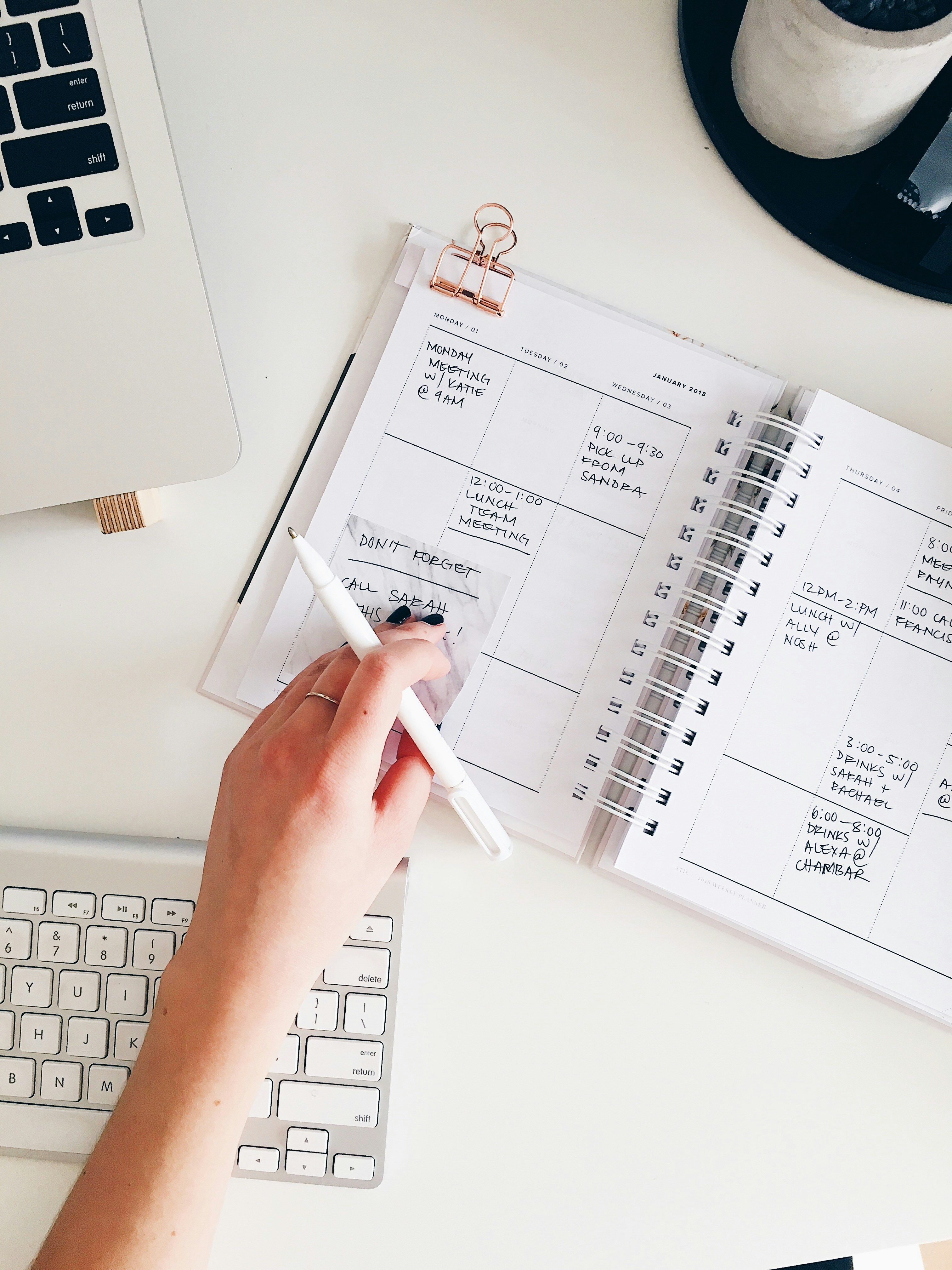 Planning a weekly schedule by hand next to a laptop